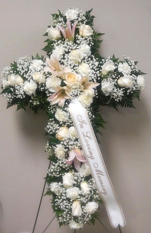 White floral funeral cross with a memorial ribbon