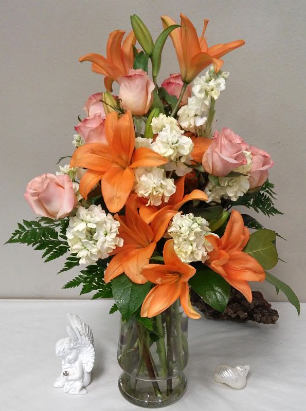 Peach Glow - What’s pretty in peach? This rich mix of orange lilies, peach roses and lovely blossoms, simply arranged in a clear glass vase, will create a warm glow in any setting. A charming bouquet for anyone who loves flowers.