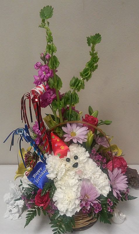 Basket arrangement with a white plush dog and colorful flowers