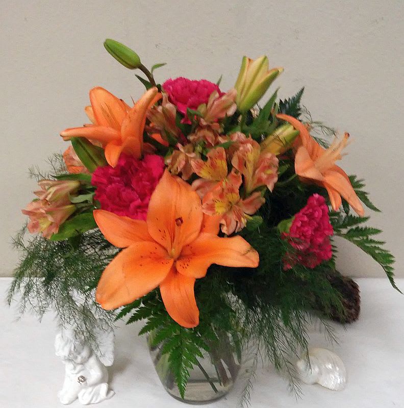 Orange lilies and pink carnations in a glass vase