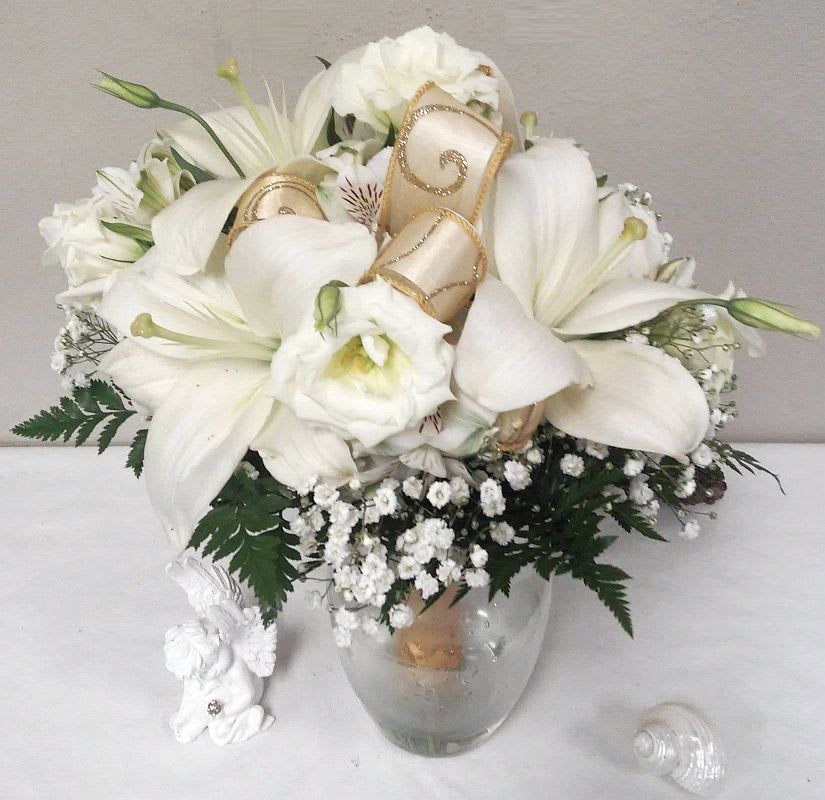 White floral bouquet in a clear glass vase with gold ribbon accents
