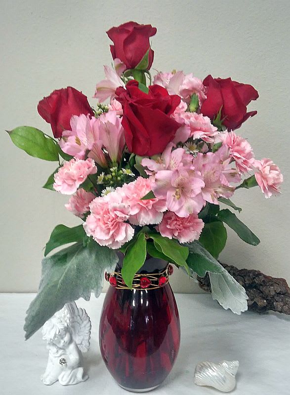 Red roses and pink flowers arranged in a burgundy vase