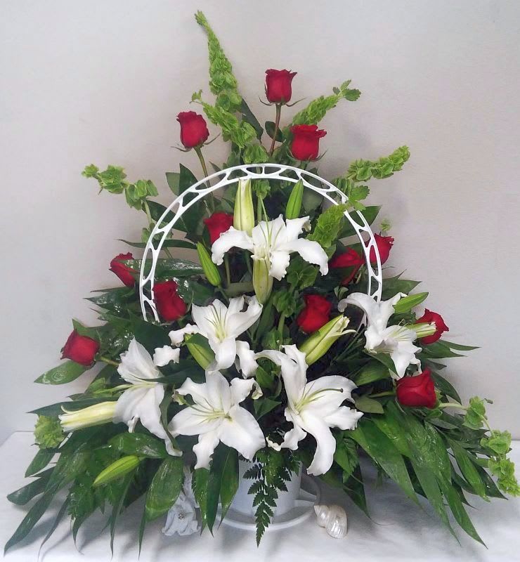 White lilies and red roses arranged in a white basket