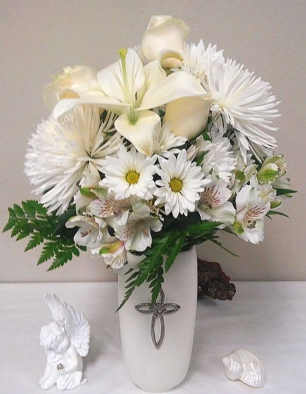 White floral arrangement in a tall vase with an angel figurine