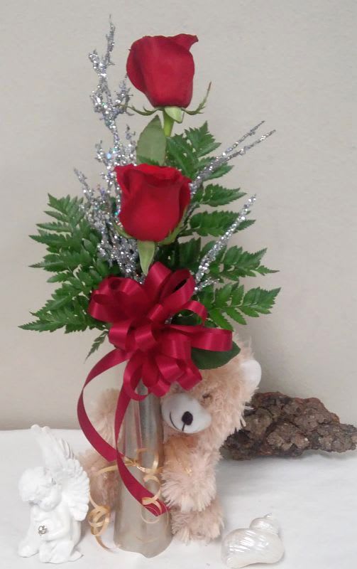 Two red roses in a silver vase with a teddy bear and ribbon