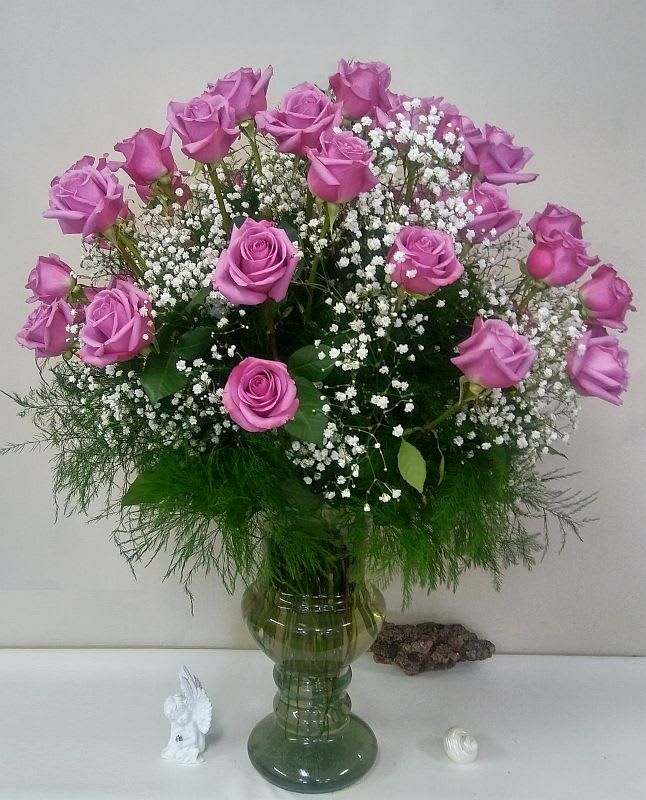 Pink roses arranged in a green glass vase with white baby's breath