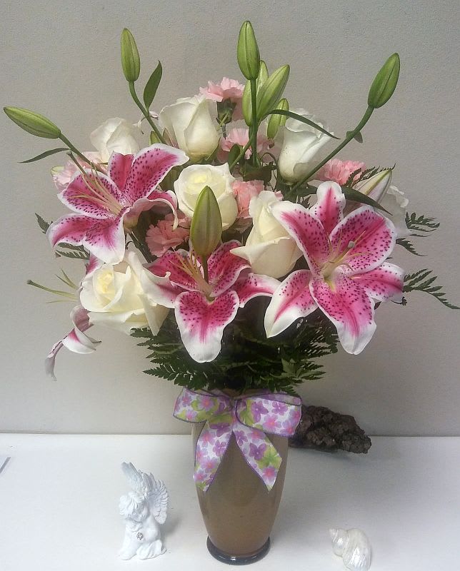Pink lilies and white roses in a vase with a ribbon bow