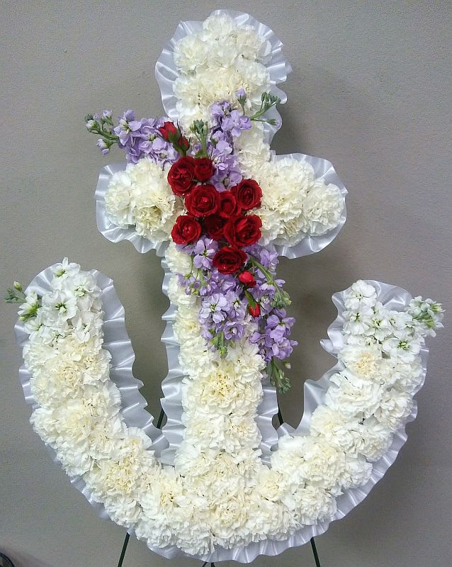 Floral cross arrangement with white flowers, red roses, and lavender blooms