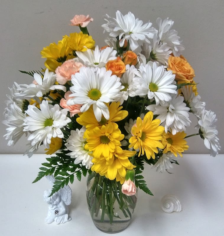 Bouquet of white and yellow daisies with peach accents in a glass vase