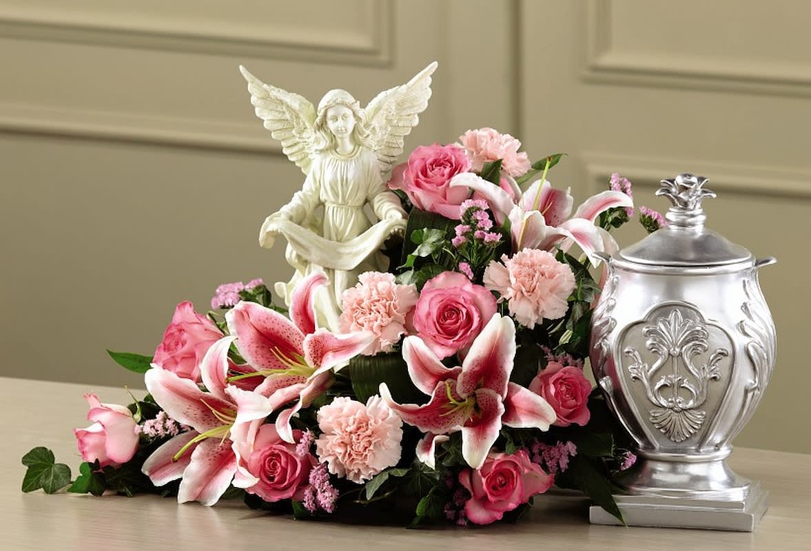 Pink roses and lilies arranged with an angel figurine and silver urn
