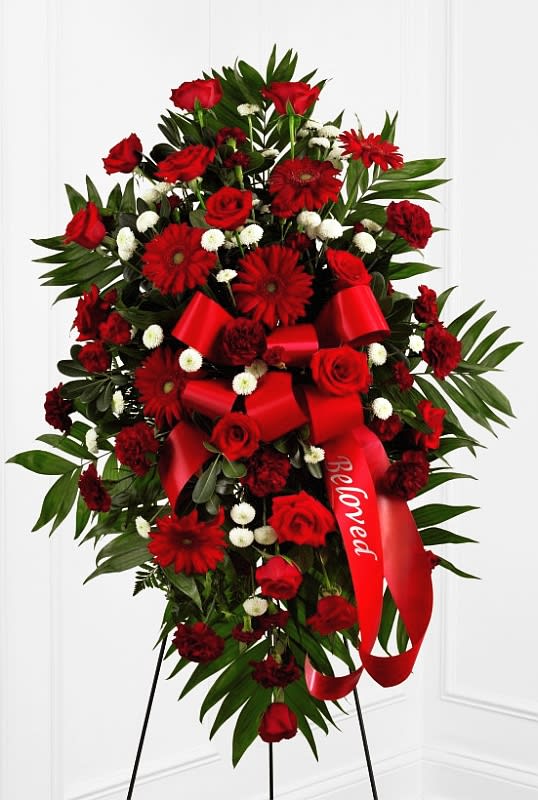 Standing spray of red roses and gerbera daisies with a red ribbon