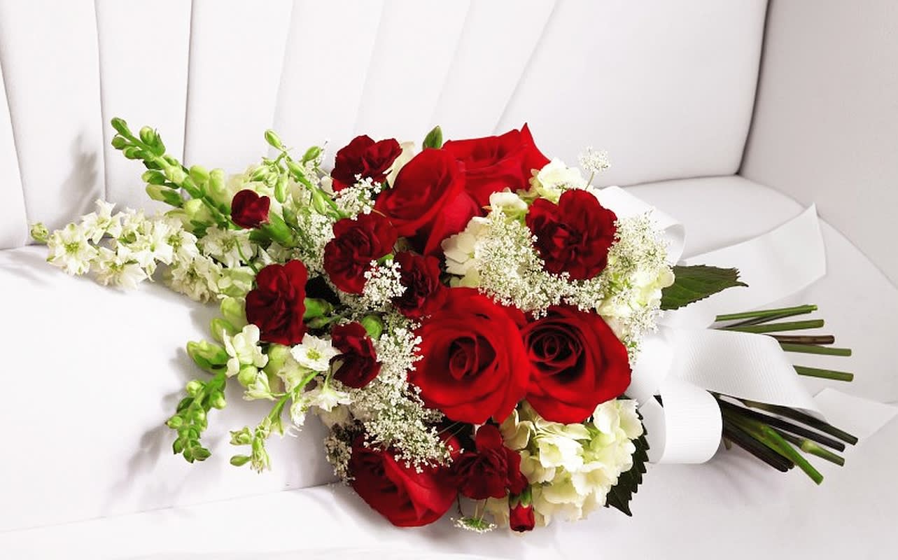 Red roses and white flowers arranged in a hand-tied bouquet