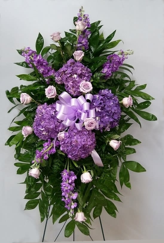 Purple floral standing spray with roses and hydrangeas on a ribboned easel