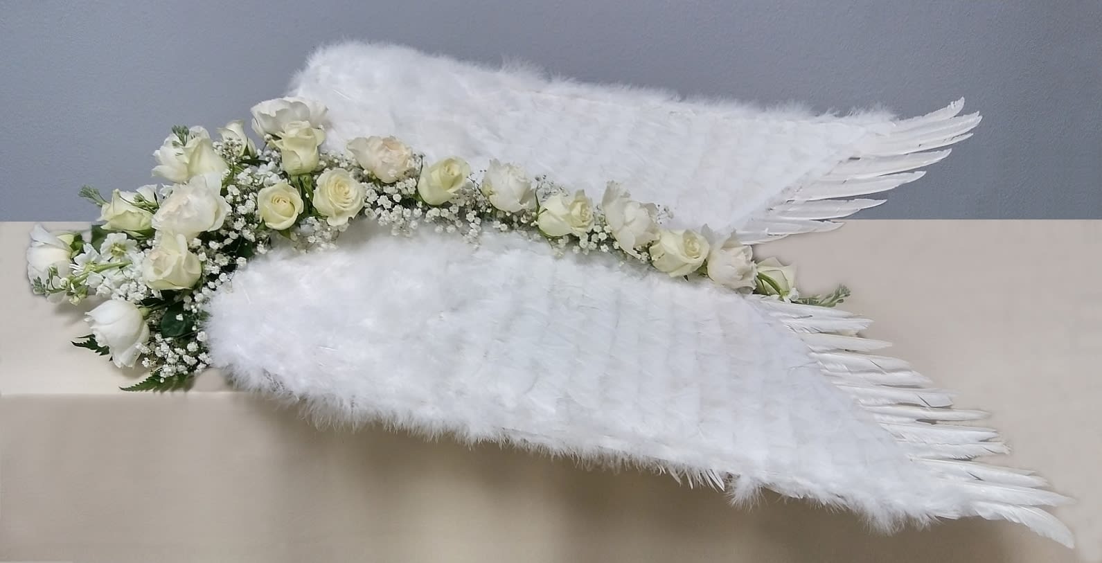 White rose floral arrangement with large white feather wings