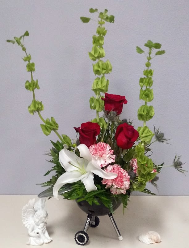 Arrangement of red roses, white lily, and pink flowers in a black vase