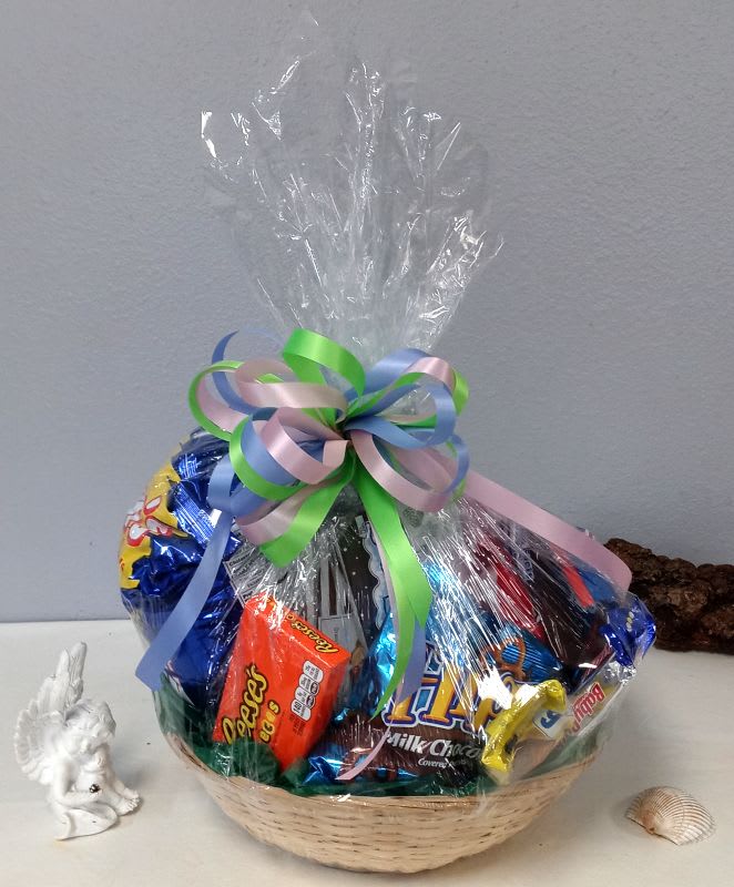 Basket of assorted candies wrapped in clear cellophane with a pastel ribbon bow