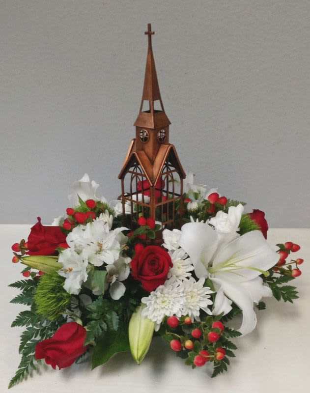 Red and white floral arrangement with a wooden church centerpiece