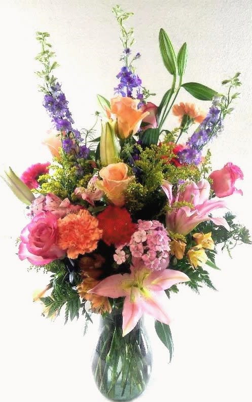 Mixed bouquet of pink, orange, and purple flowers in a glass vase