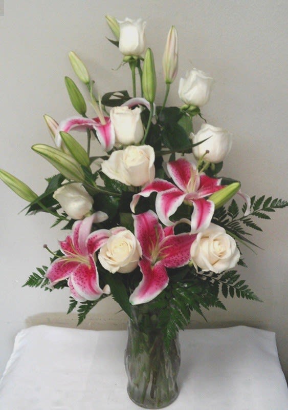 Pink lilies and white roses arranged in a clear glass vase