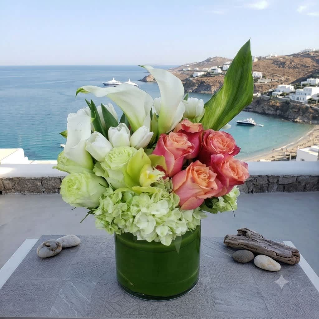 Bouquet of white calla lilies, roses, and pale green hydrangeas in a green vase