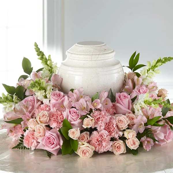 Pink roses and carnations arranged around a white urn