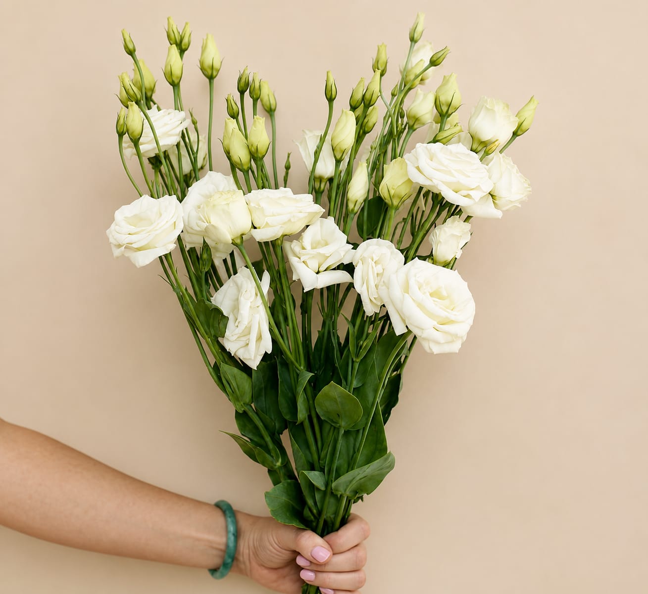 Hand holding a bouquet of white lisianthus flowers with green buds