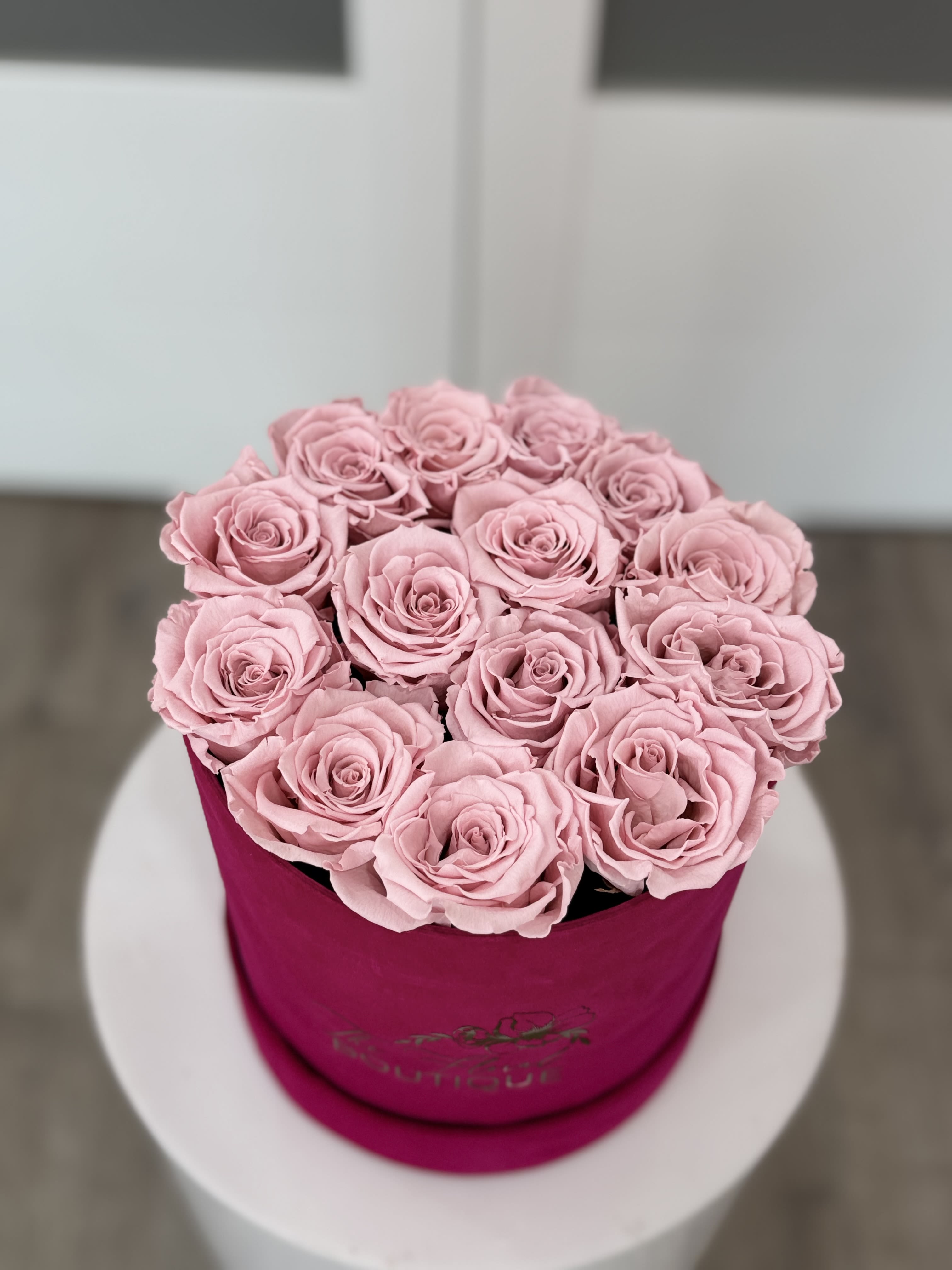 Pink roses arranged in a round magenta box