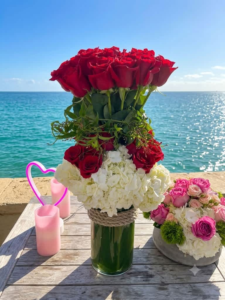 Red rose arrangement in a glass vase with white hydrangeas and pink roses