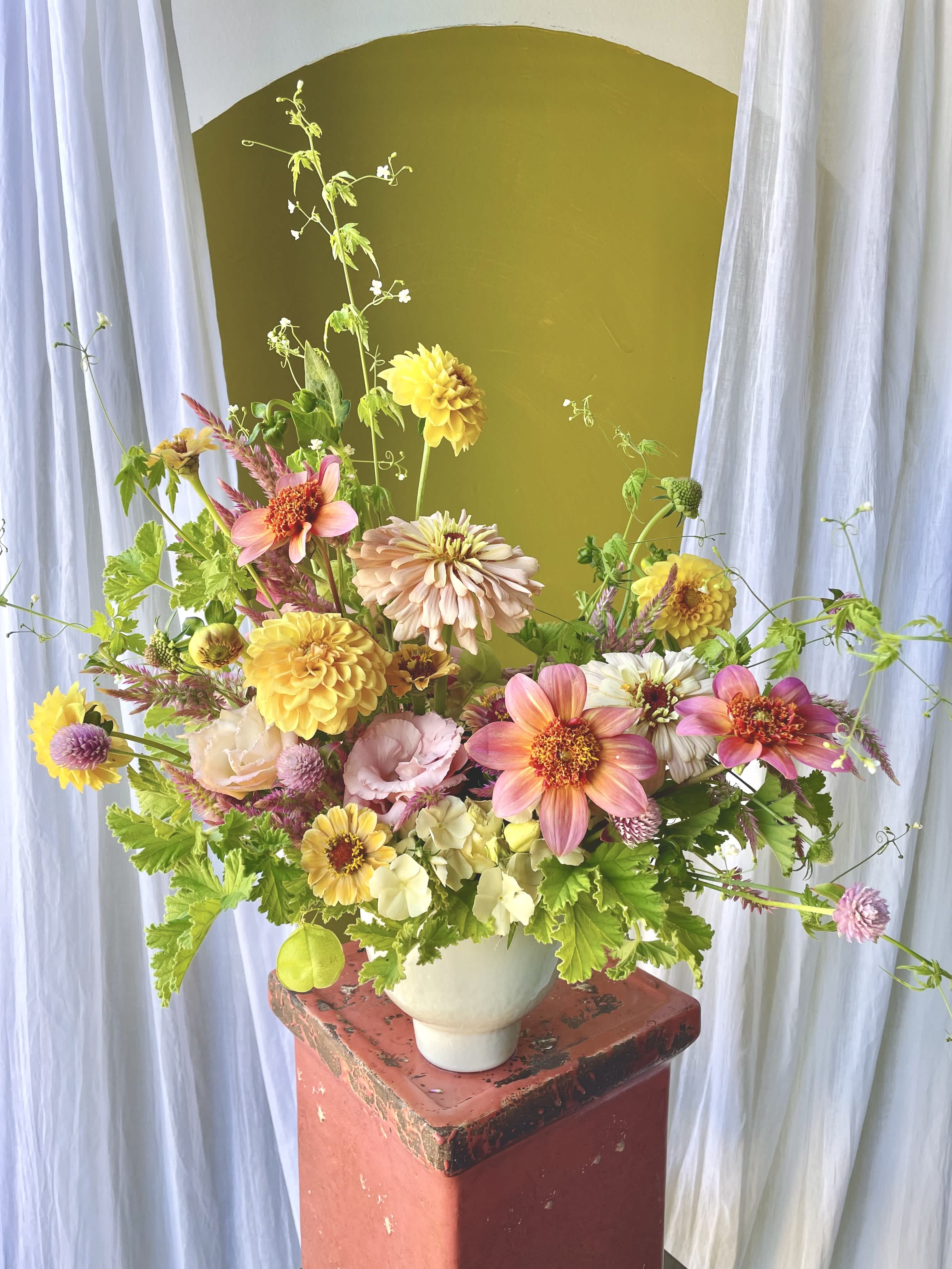 Mixed bouquet of pink, yellow, and white flowers in a white vase