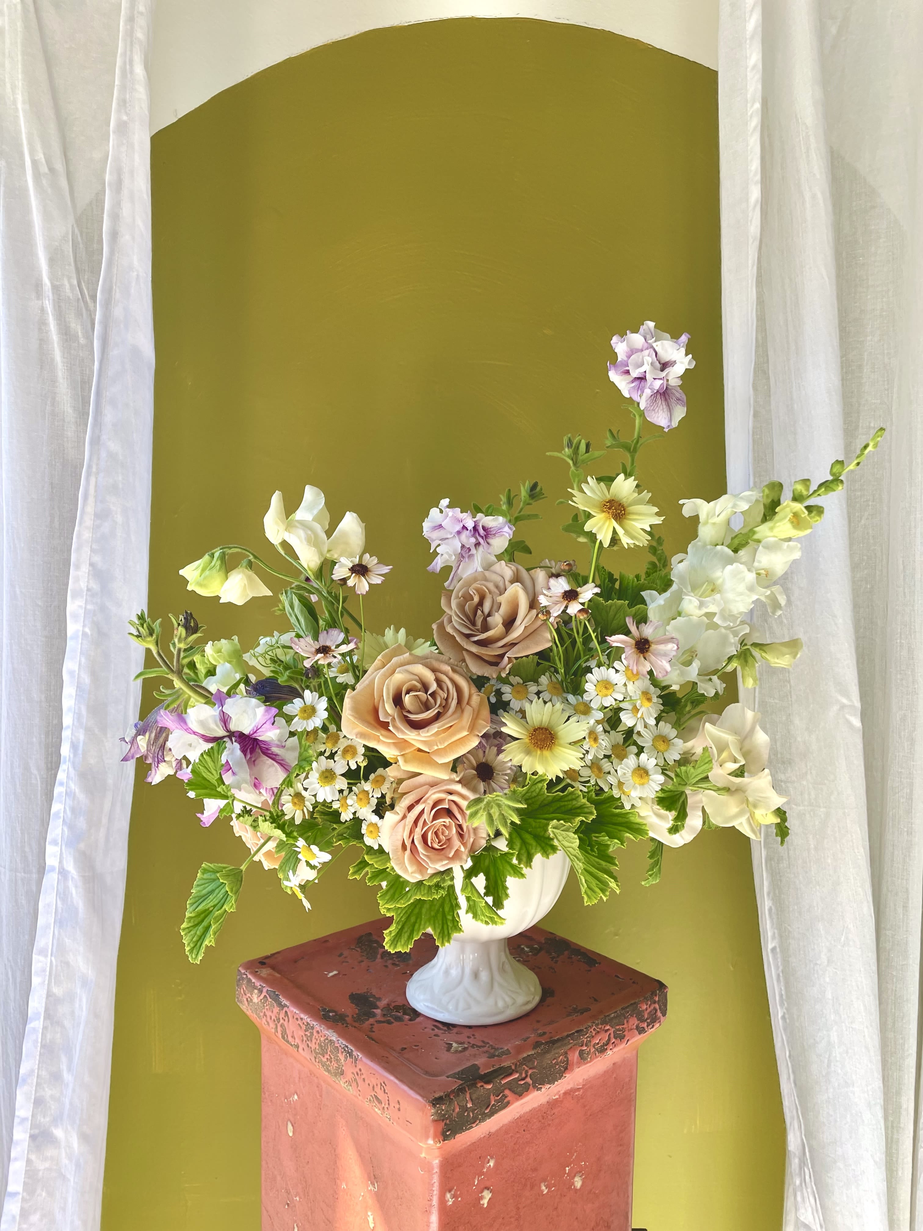 Mixed bouquet of peach roses and small white daisies in a white vase