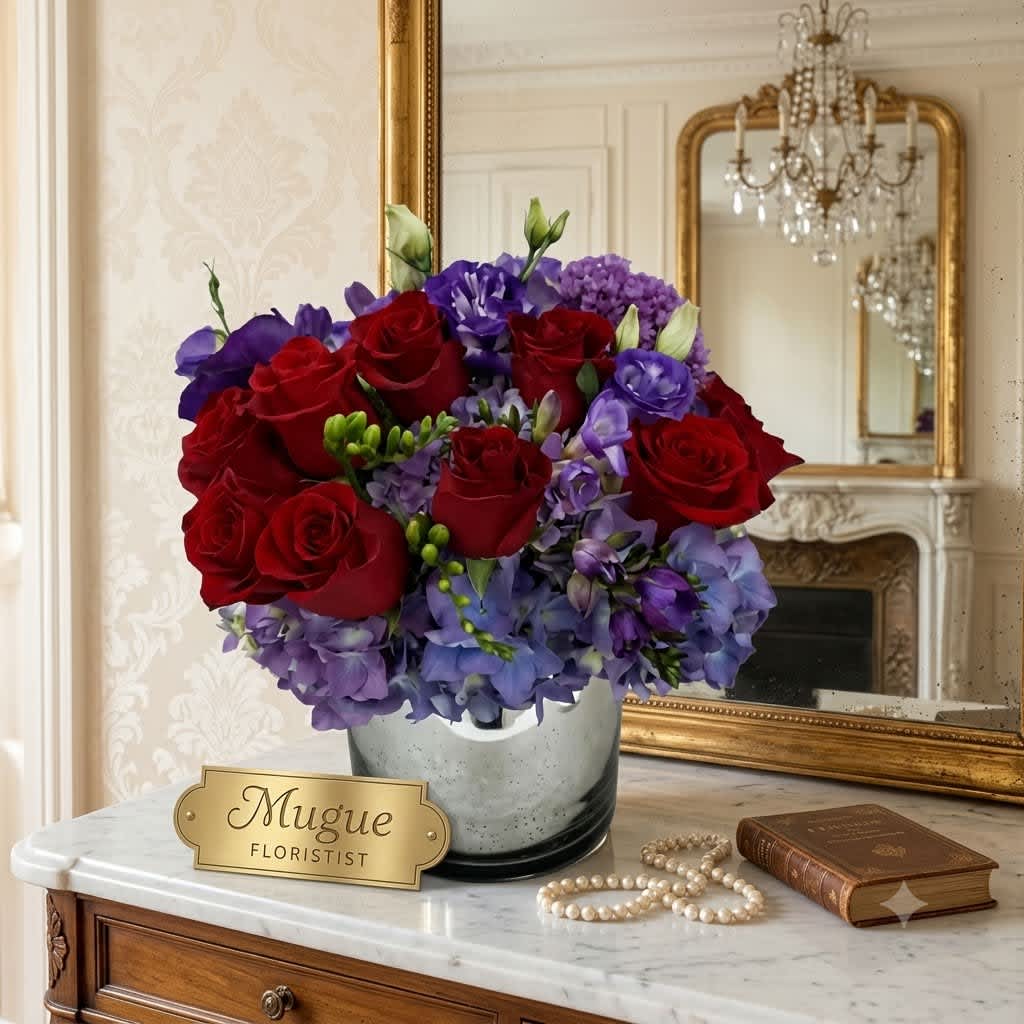 Red roses and purple flowers arranged in a silver vase