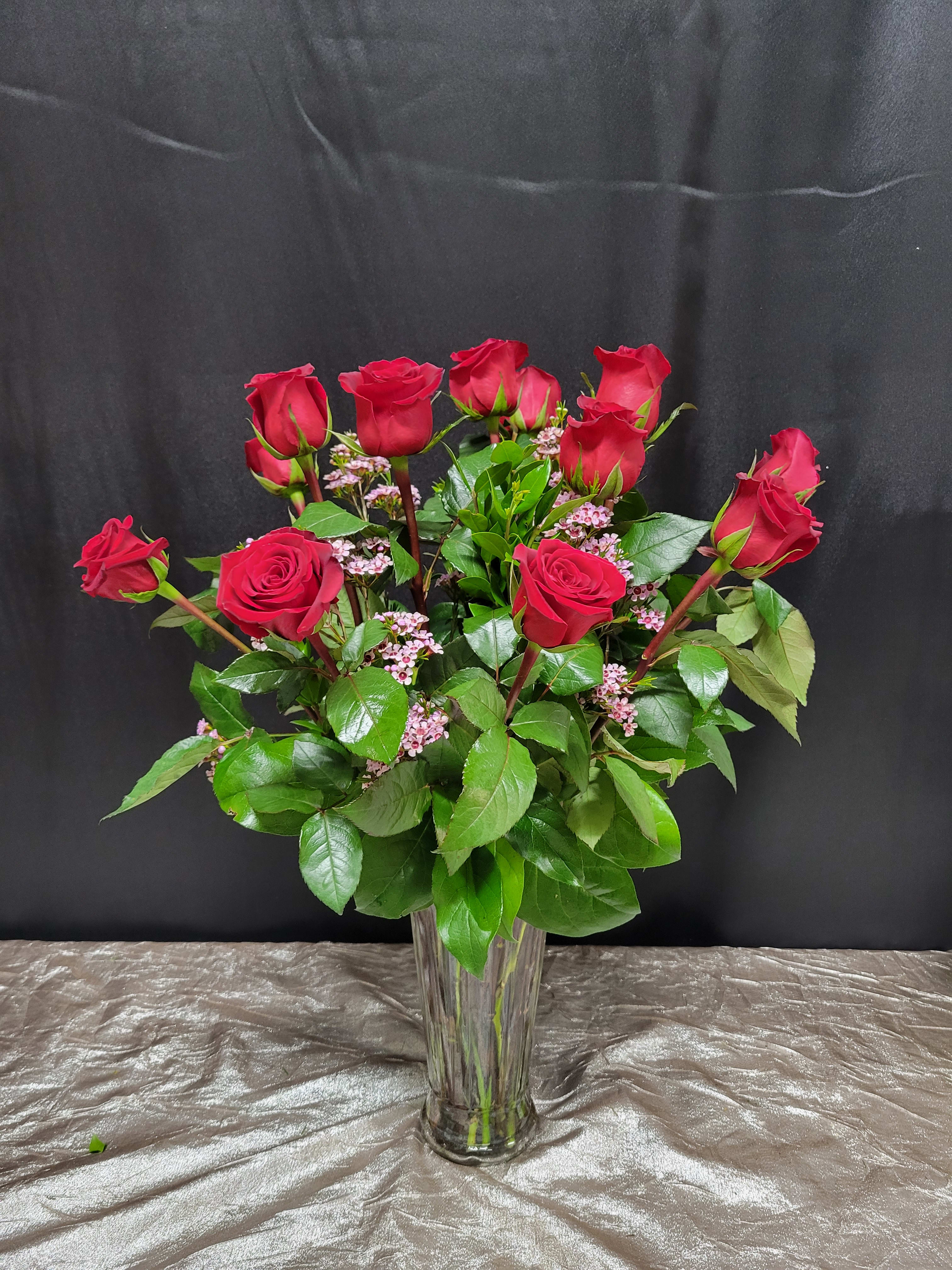 Red roses arranged in a clear glass vase with pink filler flowers