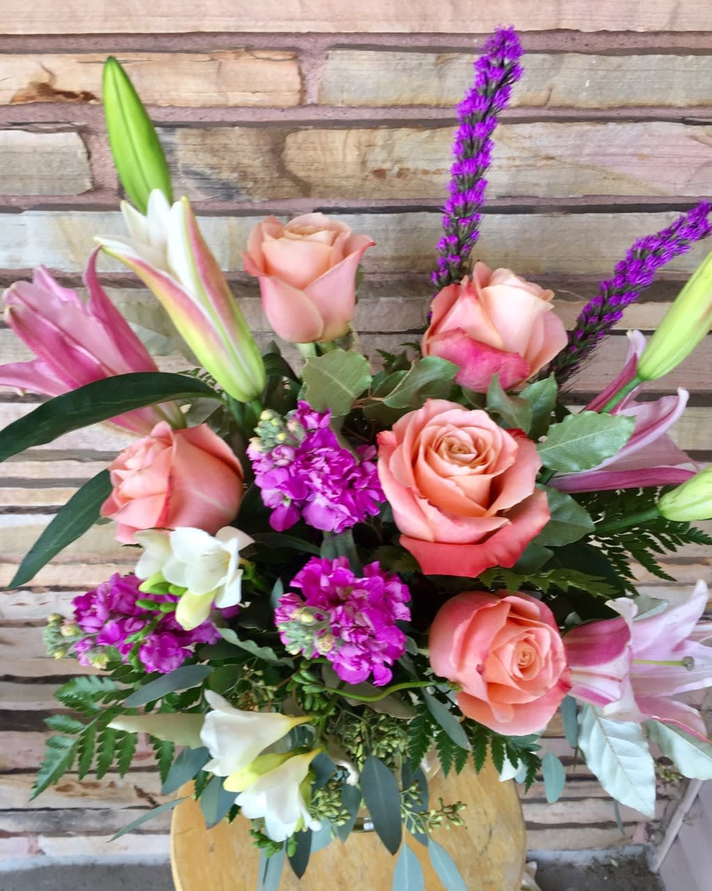 Bouquet of peach roses, lilies, and purple accent flowers