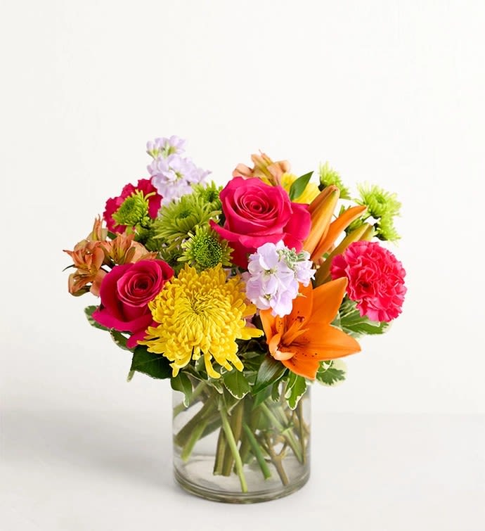 Mixed bouquet of roses, lilies, and chrysanthemums in a glass vase
