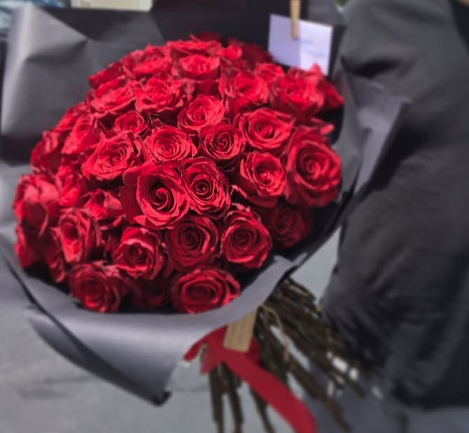 Bouquet of red roses wrapped in black paper with a red ribbon