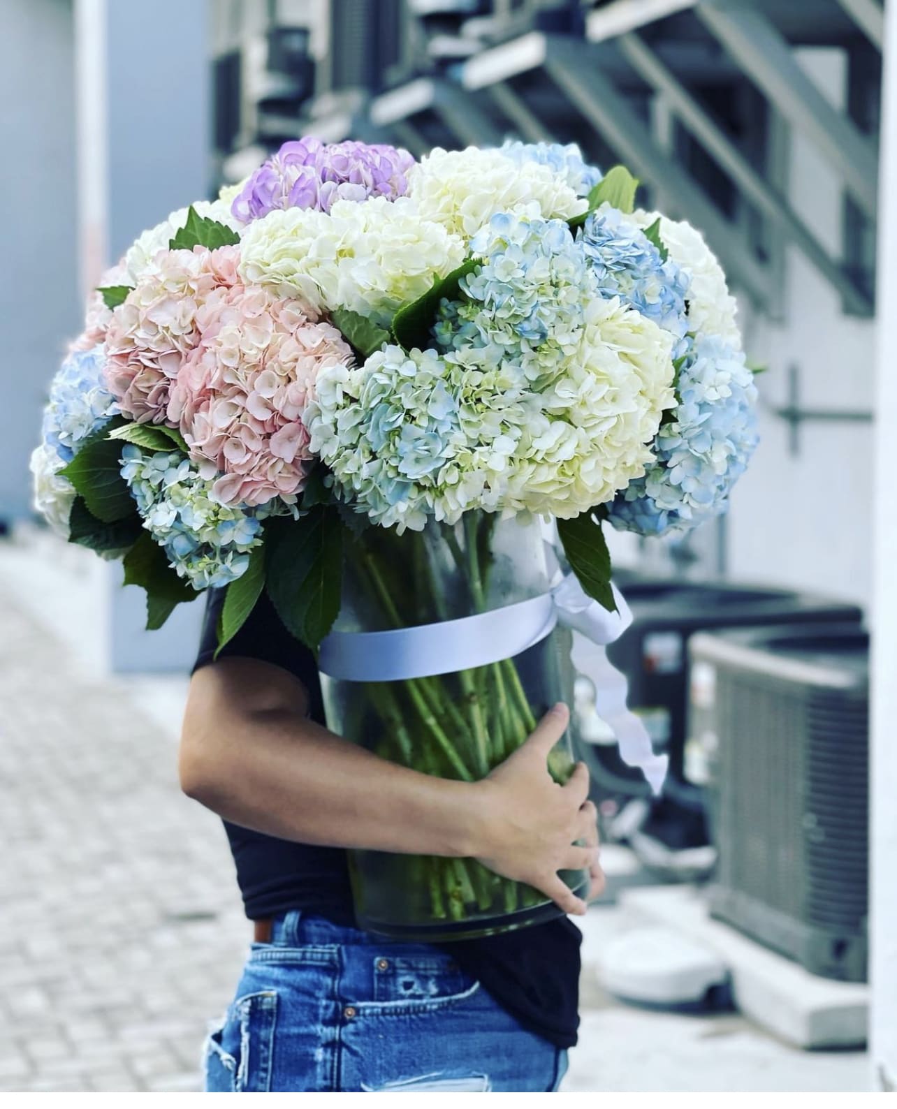 Large bouquet of pastel hydrangeas in a glass vase with a ribbon