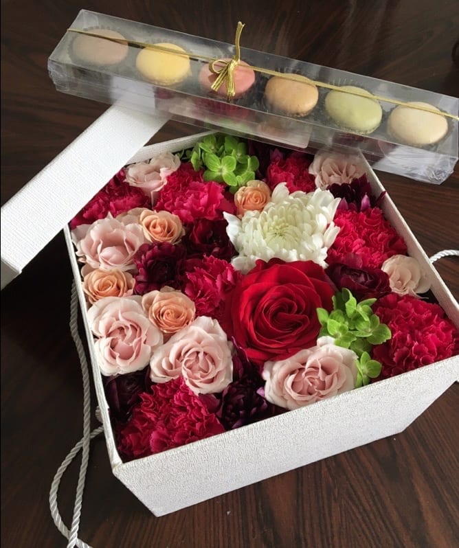 Box of mixed roses and carnations with macarons on top