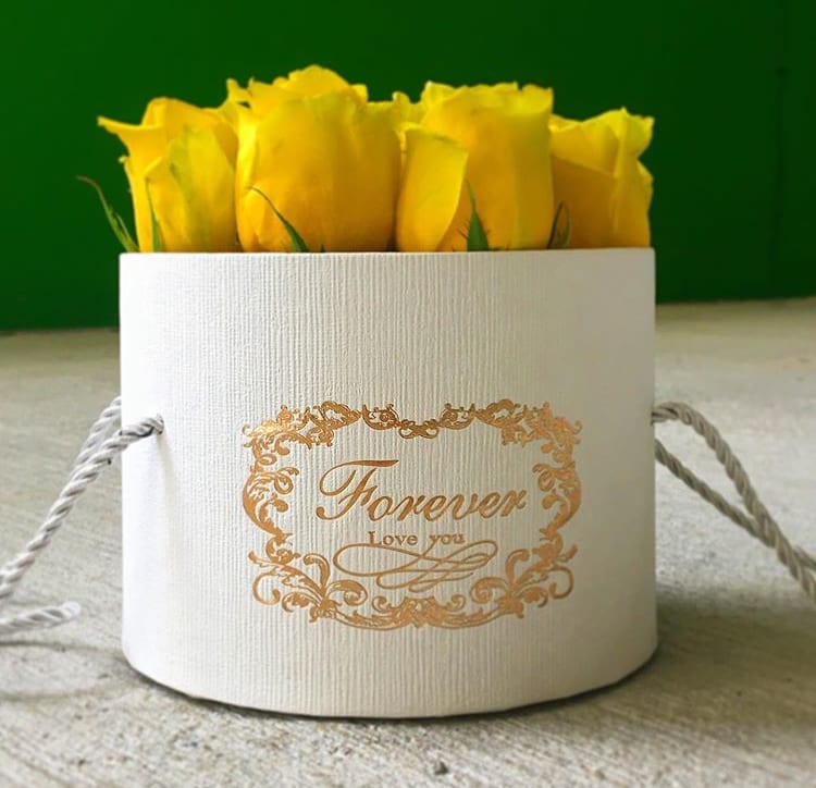 Yellow roses in a white round gift box with gold lettering