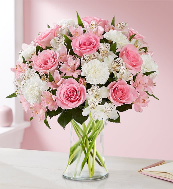 Pink roses and white flowers arranged in a clear glass vase