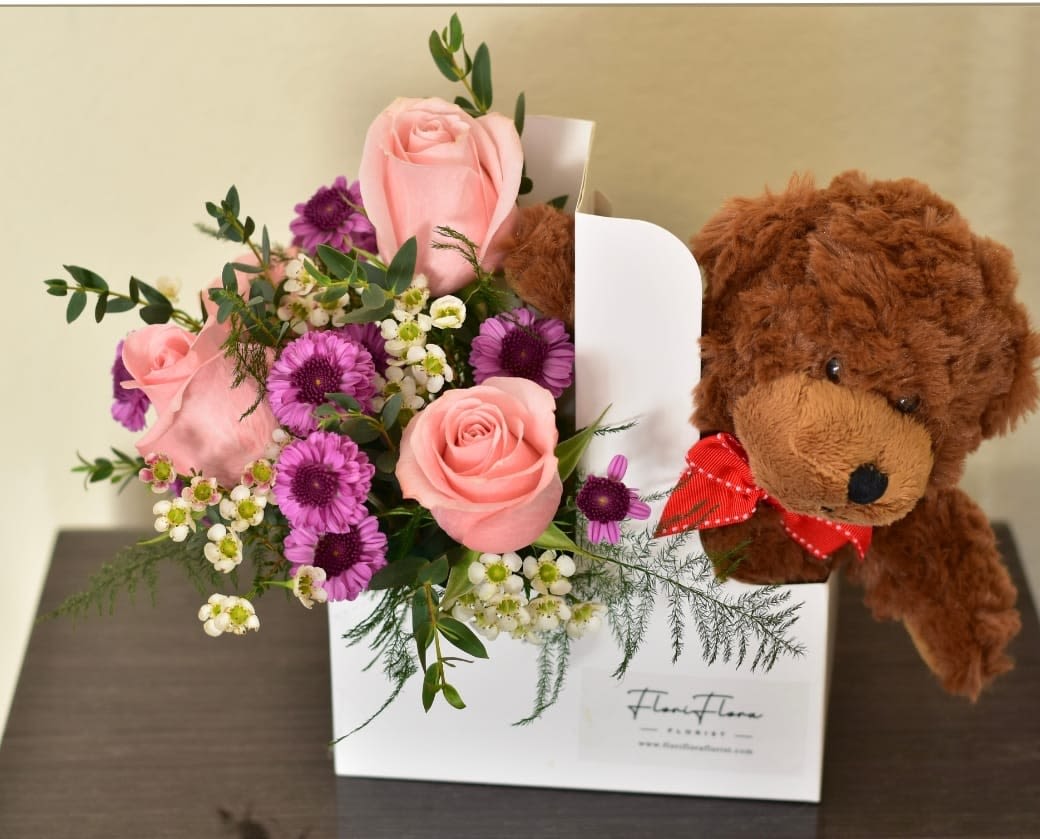 Teddy's Valentine -  Teddy’s Valentine  Celebrate love in the most adorable way with Teddy’s Valentine—a heartwarming floral arrangement paired with a cuddly teddy bear, all nestled in a convenient cup holder. On one side, a delicate bouquet of fresh blooms radiates romance, while on the other, a soft teddy bear awaits with open arms, ready to deliver hugs and sweetness. Perfect for surprising your special someone, this thoughtful gift is a delightful blend of love, comfort, and charm. Whether it's for a partner, a friend, or a secret crush, Teddy’s Valentine is a sip of happiness and a hug of love in one! 