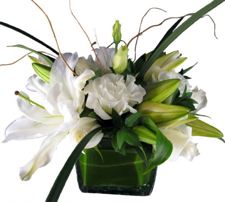 White lilies and ruffled white blooms in a green vase