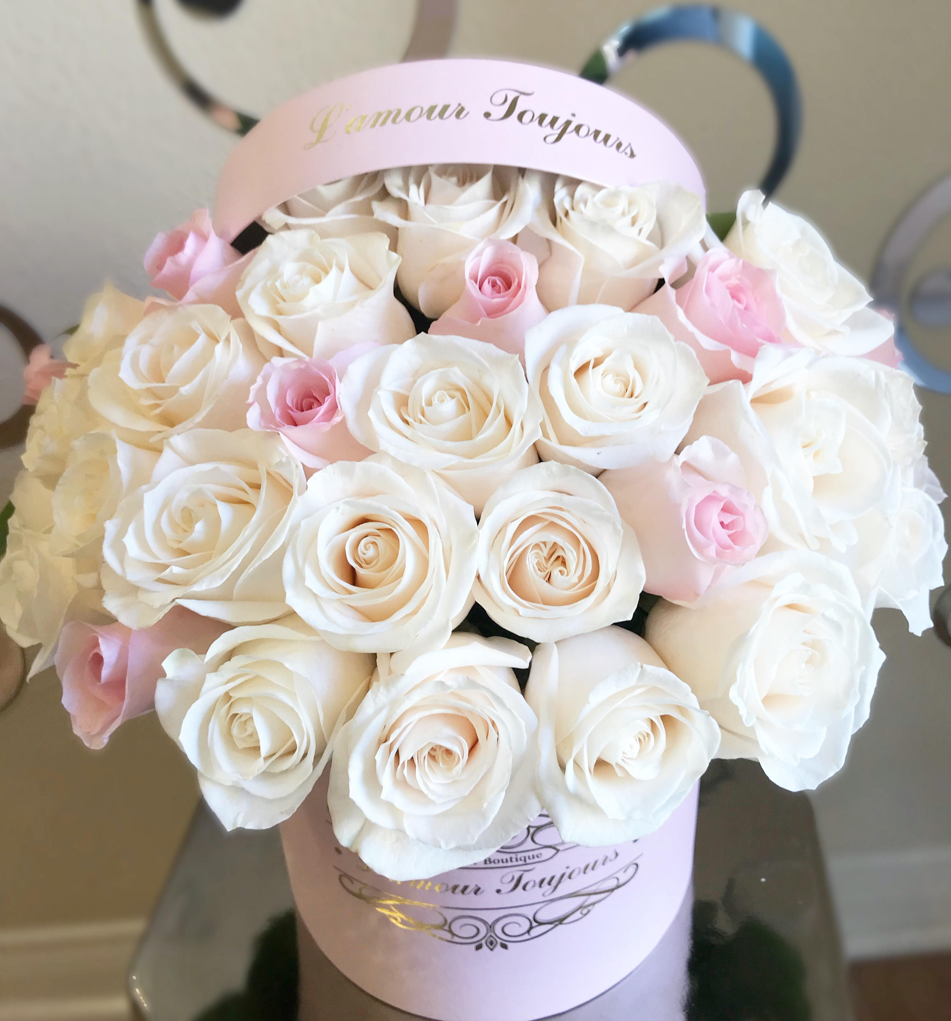 Bouquet of white and pale pink roses in a pink hatbox
