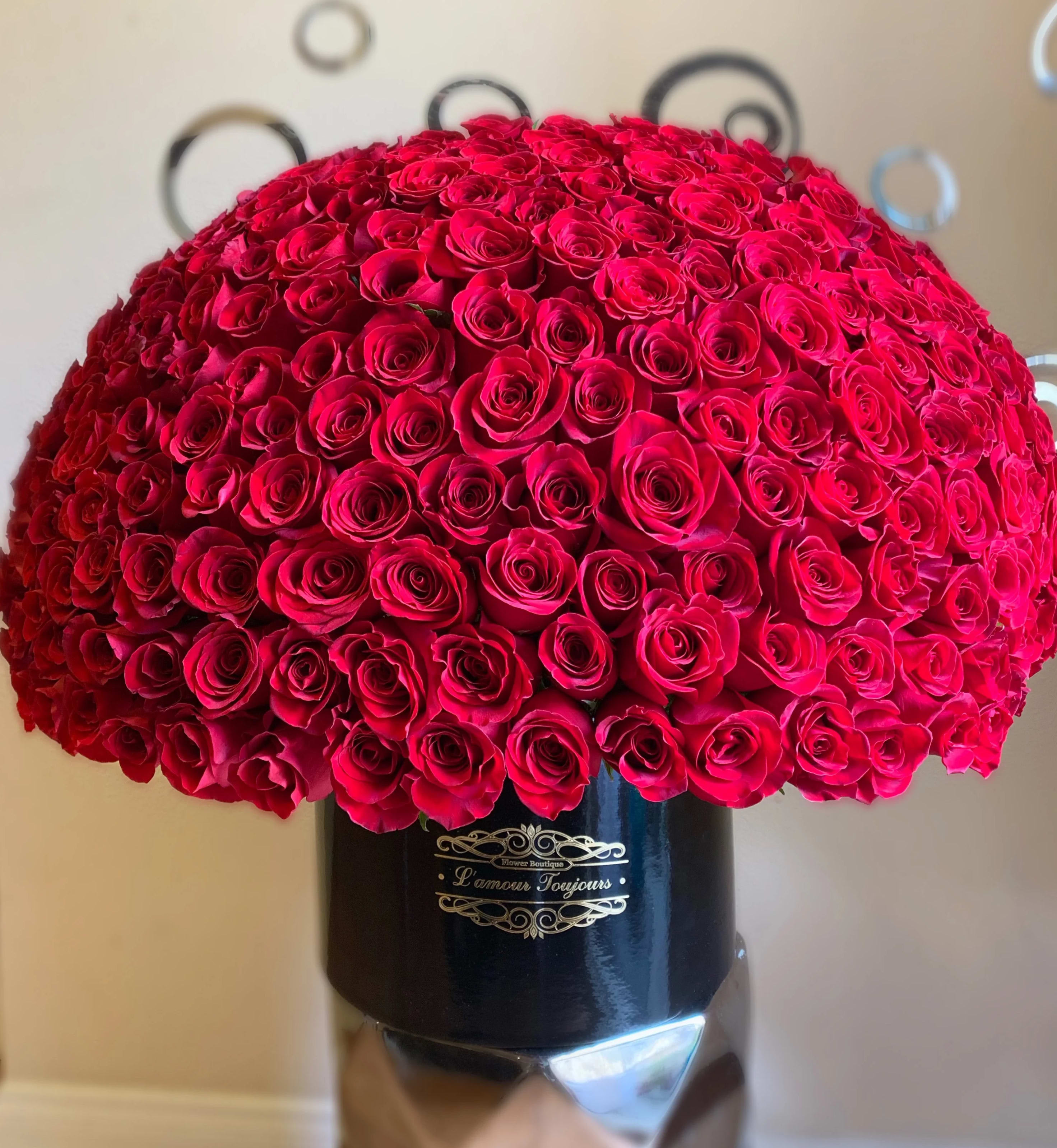 Large dome of red roses tightly arranged in a black hat box-style container