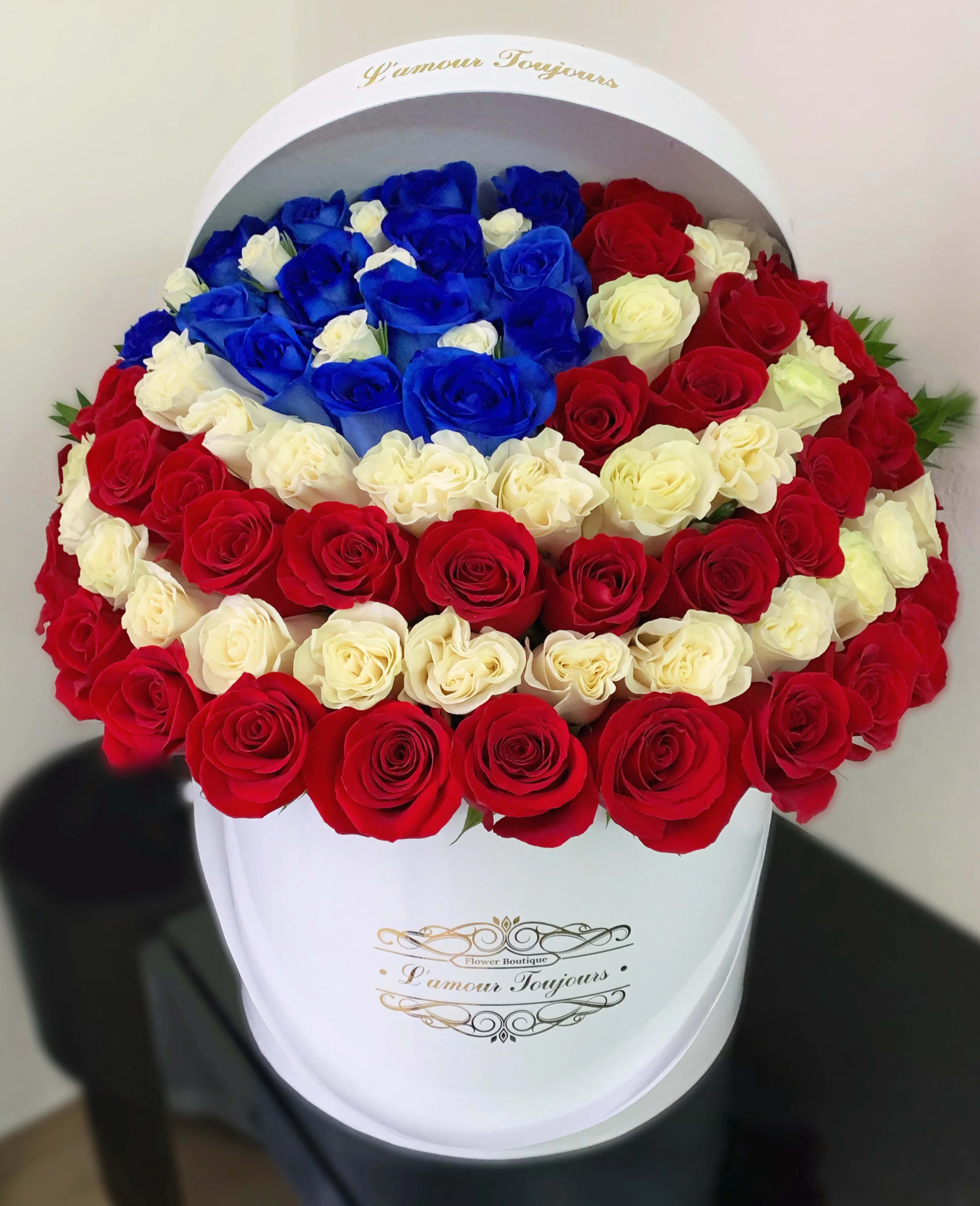 Round box arrangement of red, white, and blue roses
