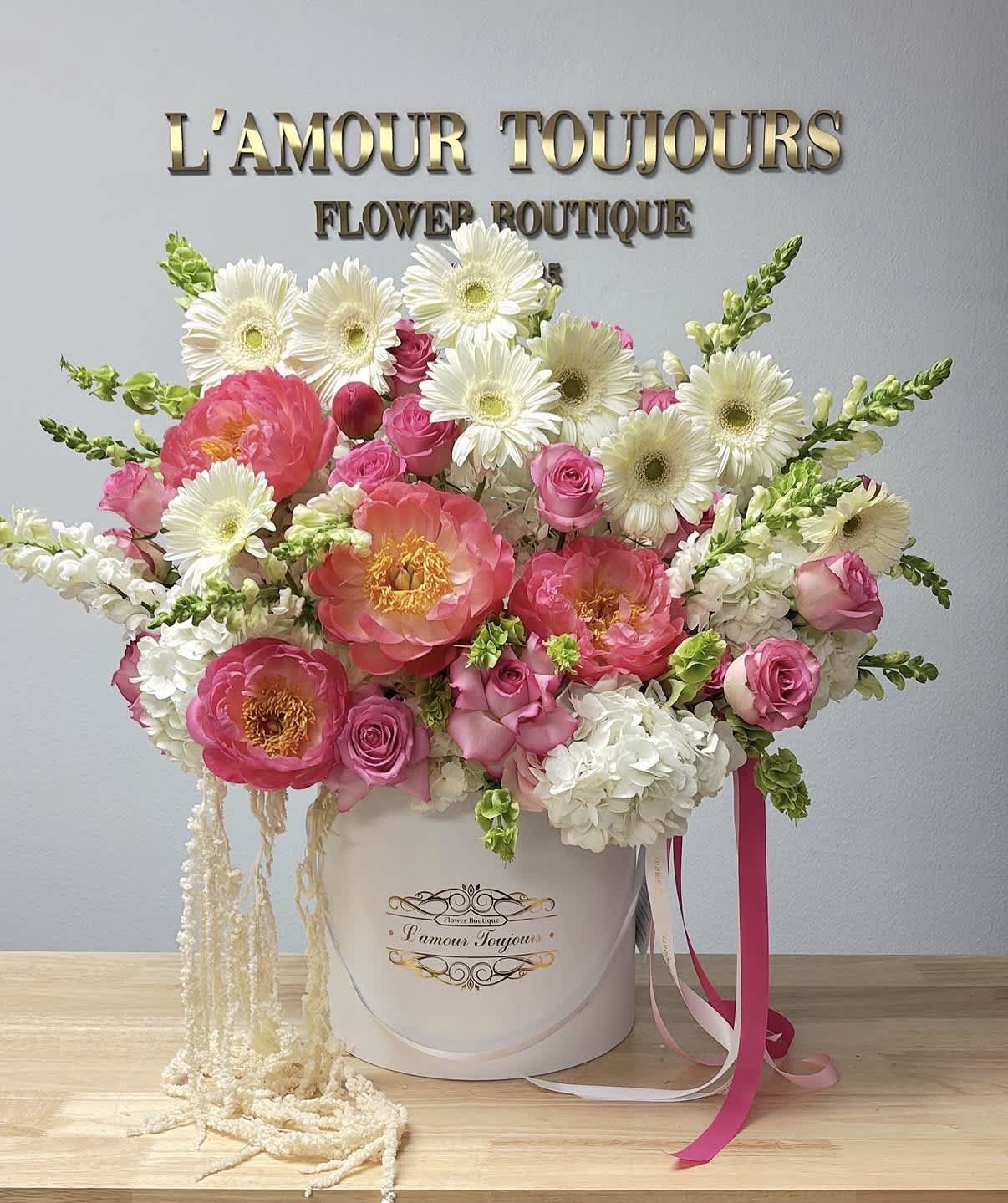 Pink and white flower arrangement in a white hat box with ribbons