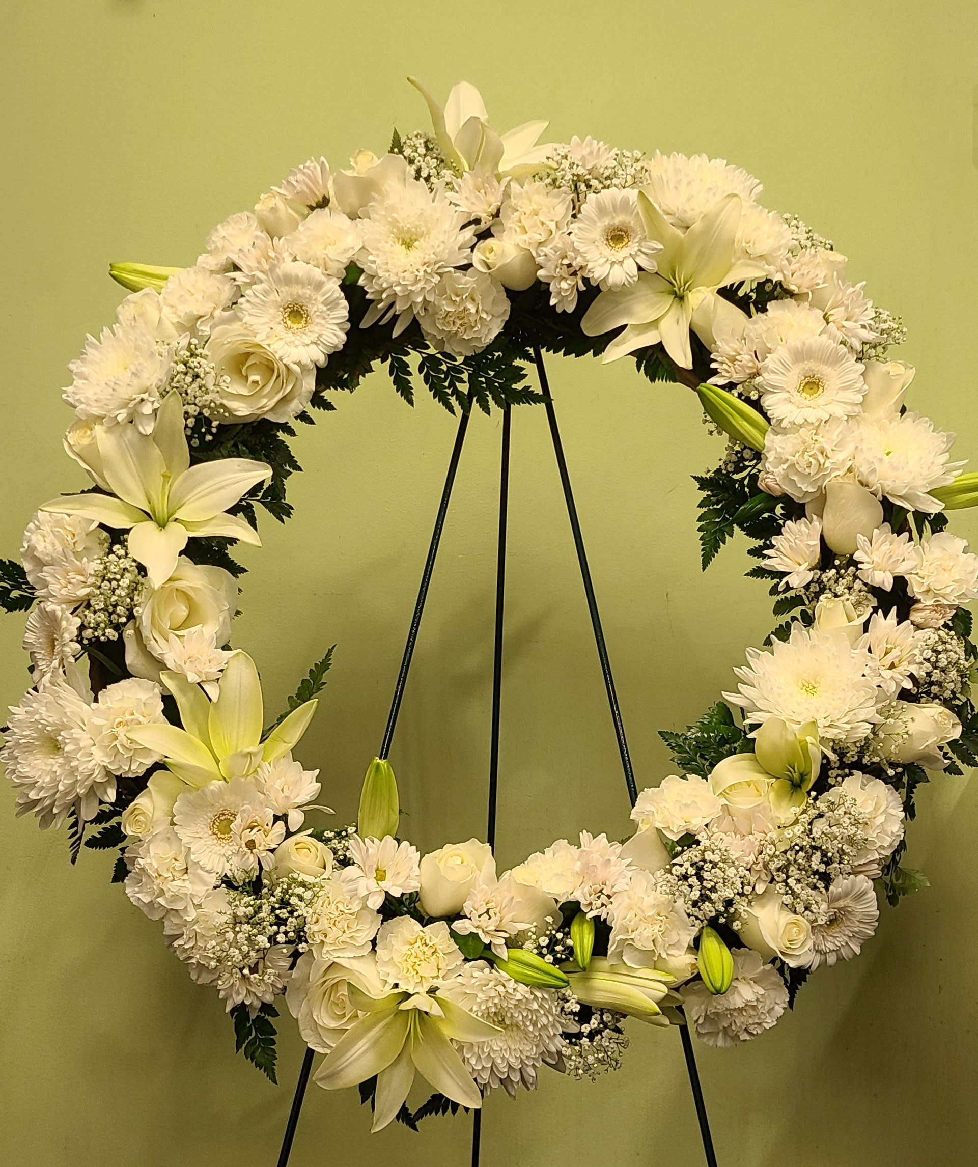 White floral wreath on a black stand