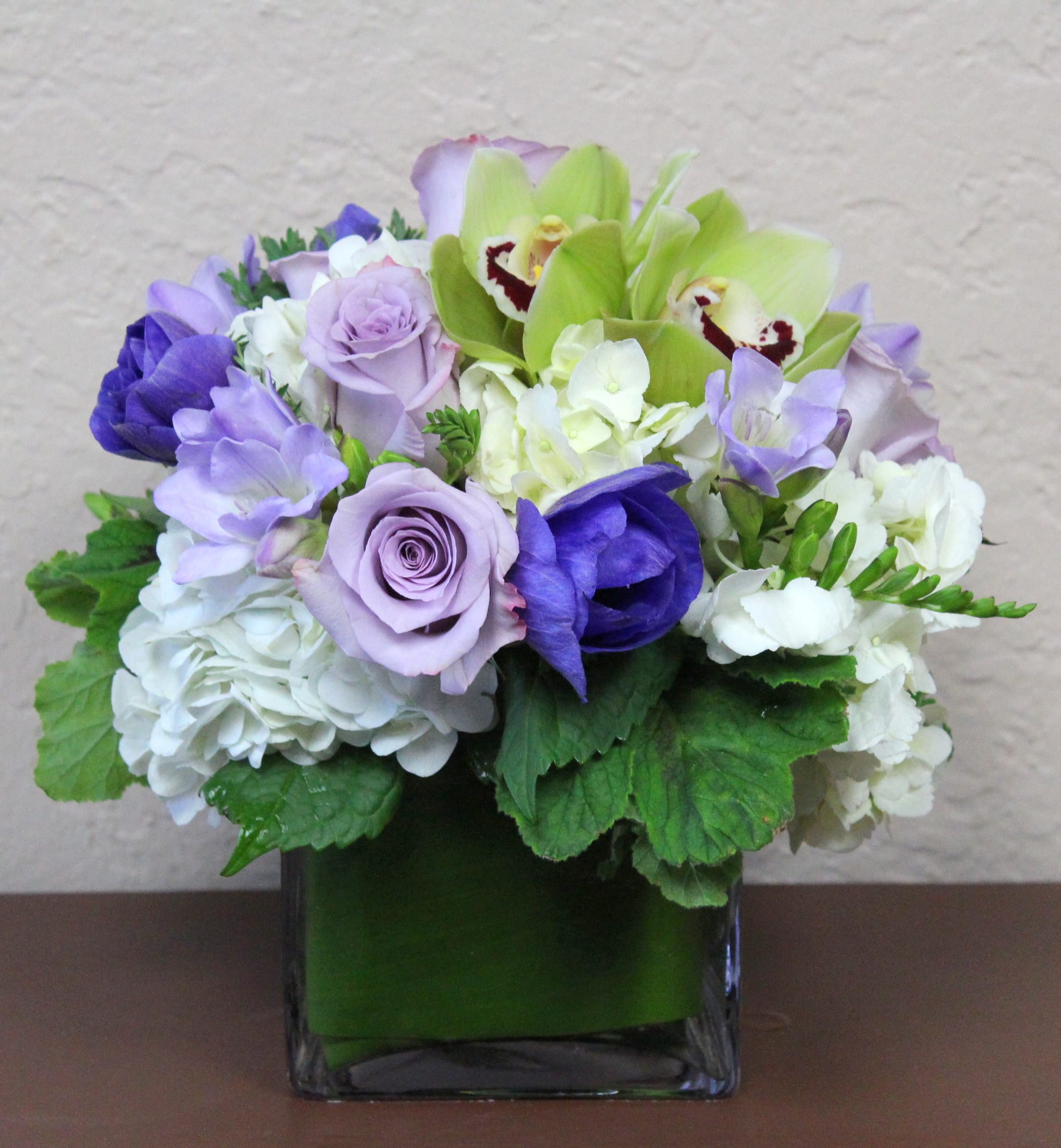 Lavender and white floral arrangement in a square glass vase
