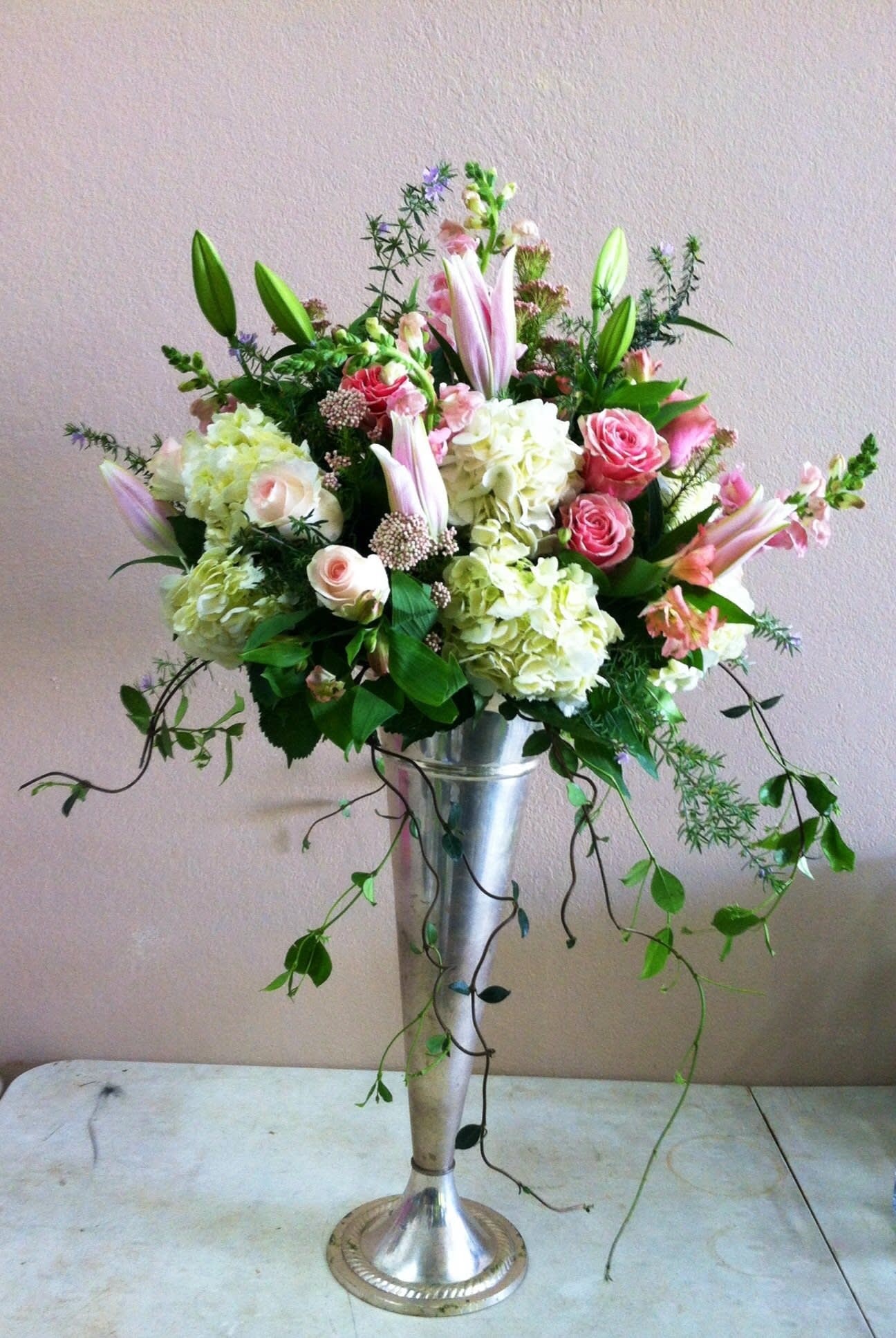 Tall floral arrangement in a silver pedestal vase with pink and white blooms
