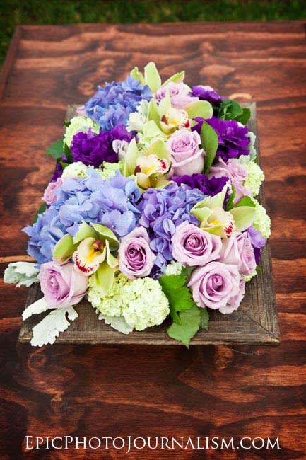 Bouquet of lavender roses, blue hydrangeas, and orchids on a wooden tray