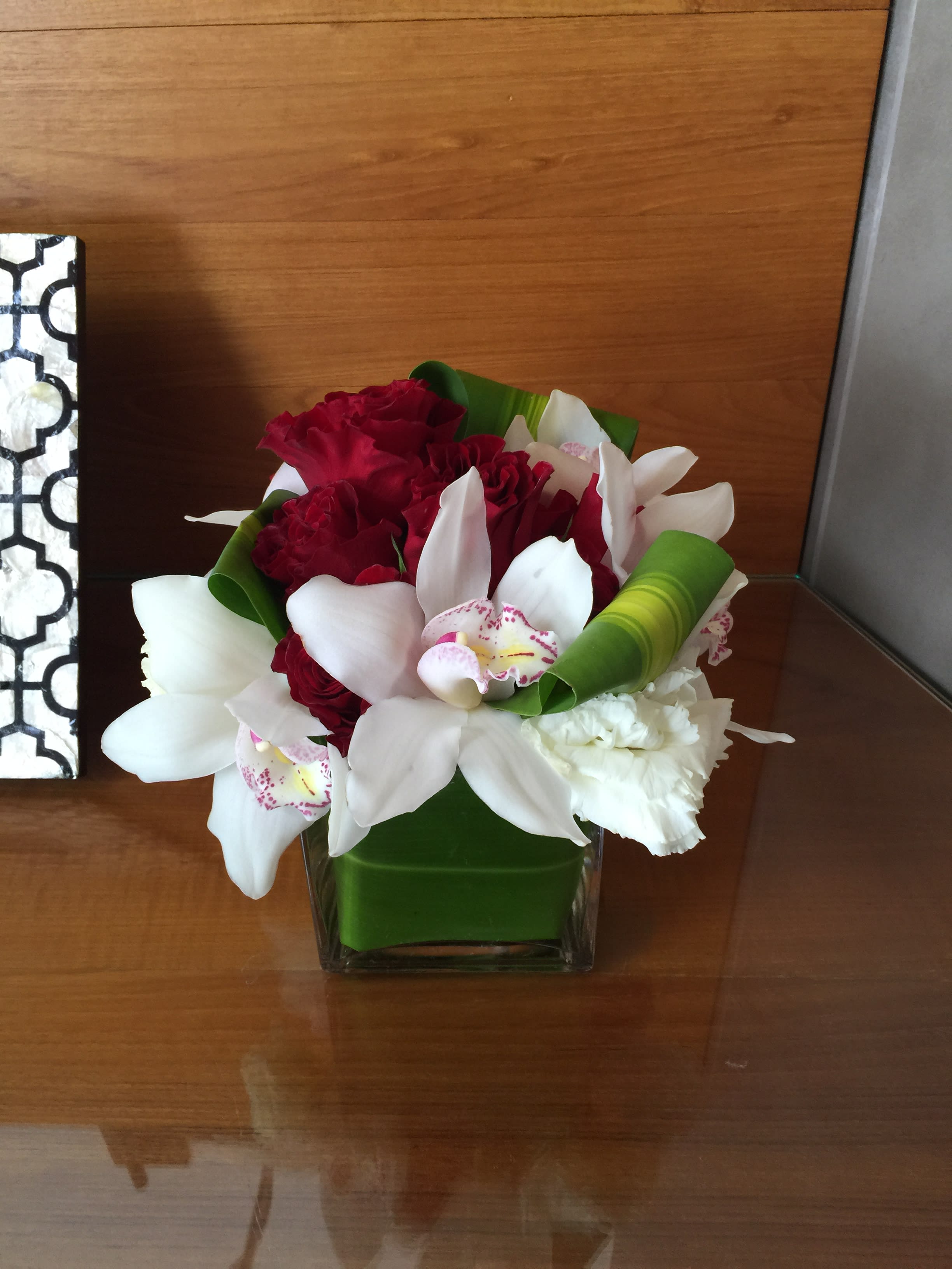 Bouquet of red and white flowers in a square glass vase